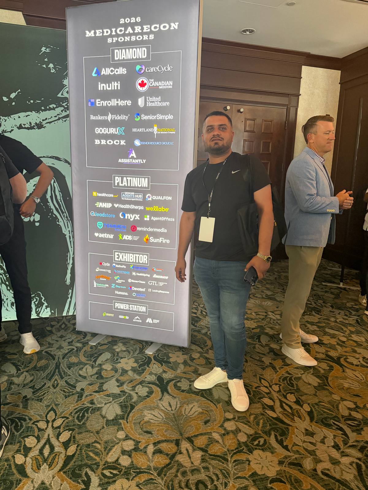 Wali Zuberi standing next to the MedicareCon 2026 sponsors banner at Ross Bridge Resort in Hoover, Alabama