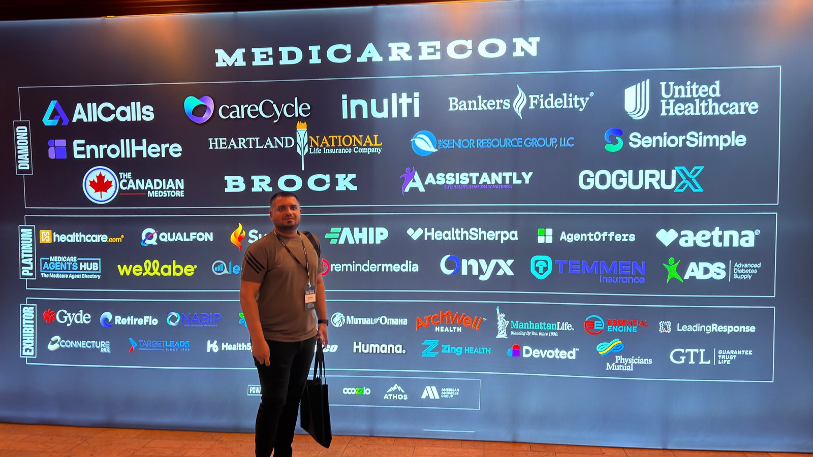 Wali Zuberi in front of the MedicareCon 2026 sponsor wall at Ross Bridge Resort, Birmingham, Alabama
