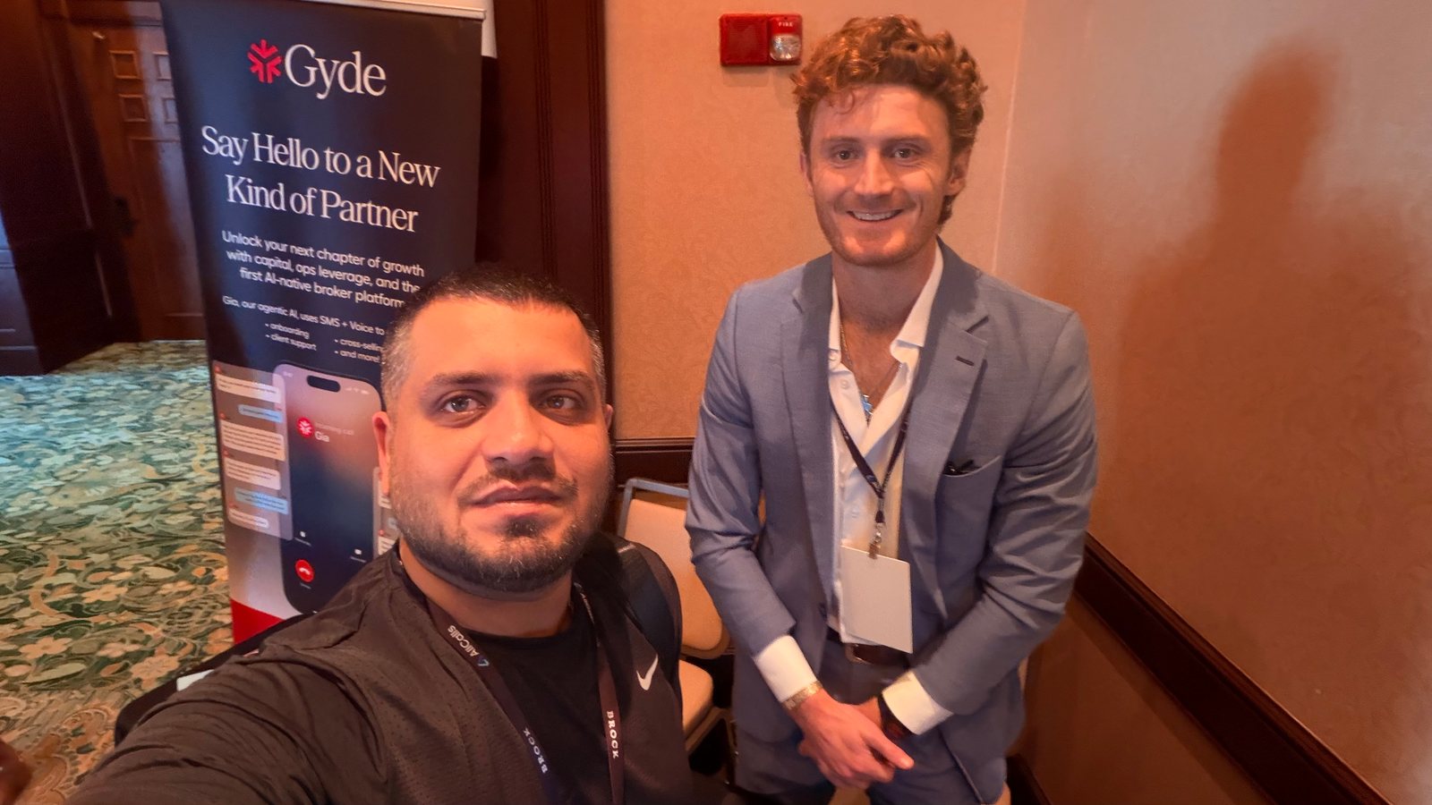 Wali Zuberi taking a selfie with an attendee near an exhibitor banner at MedicareCon 2026
