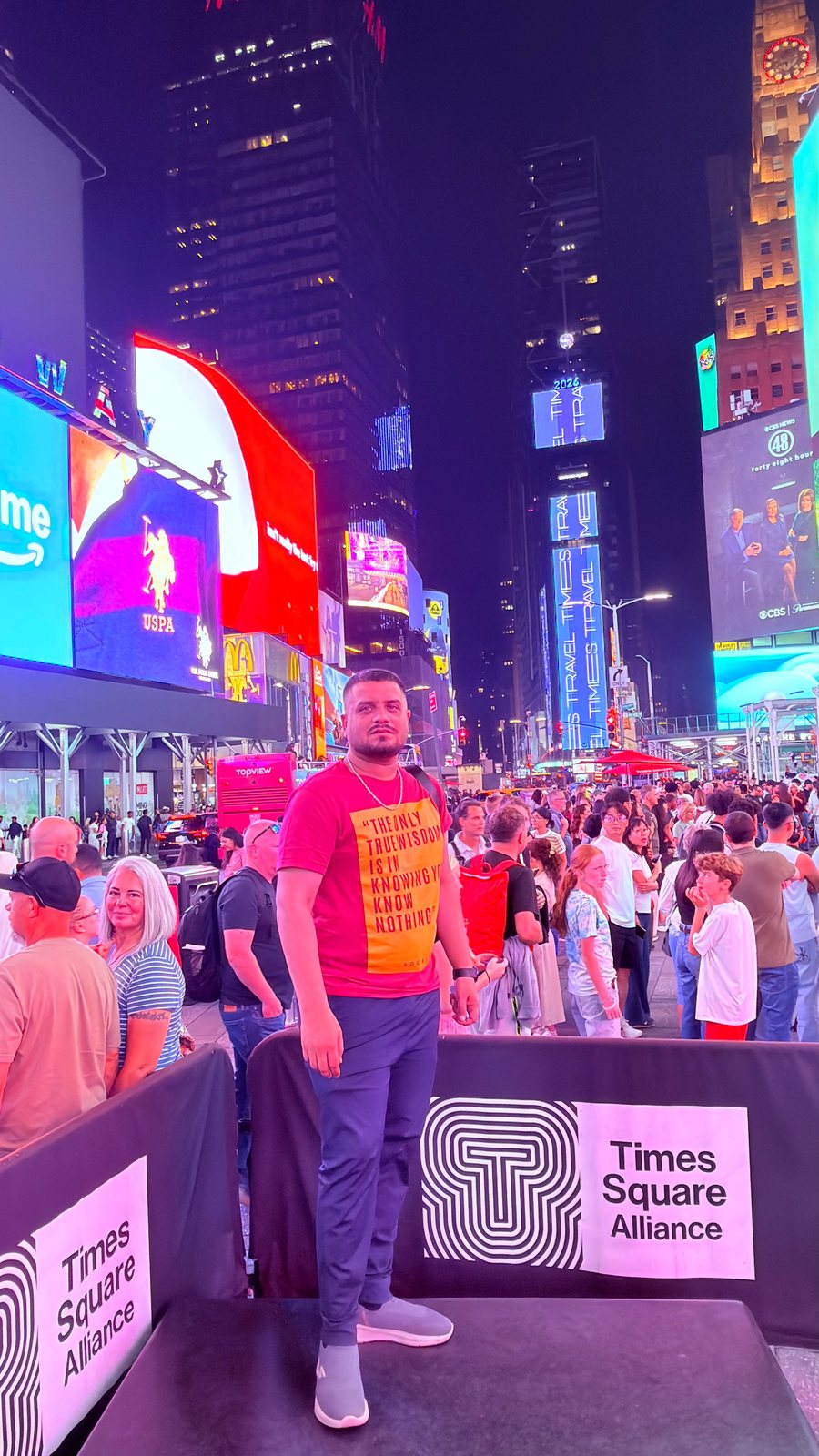 Wali Zuberi in Times Square at night surrounded by illuminated billboards
