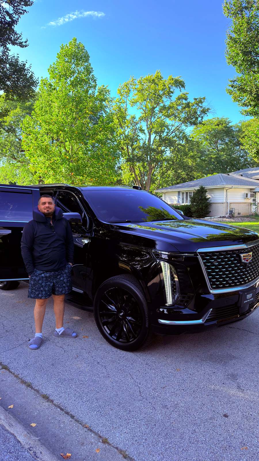 Wali Zuberi standing beside a black SUV on a residential street in the United States